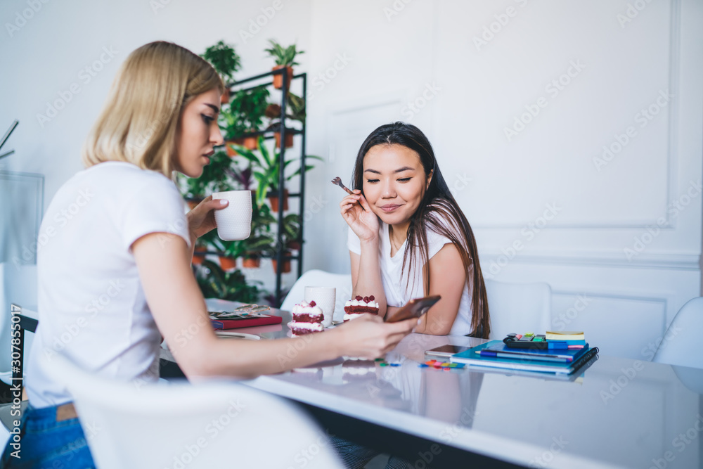 Young women texting on cellphone in creative workplace Young women texting on cellphone in creative workplace