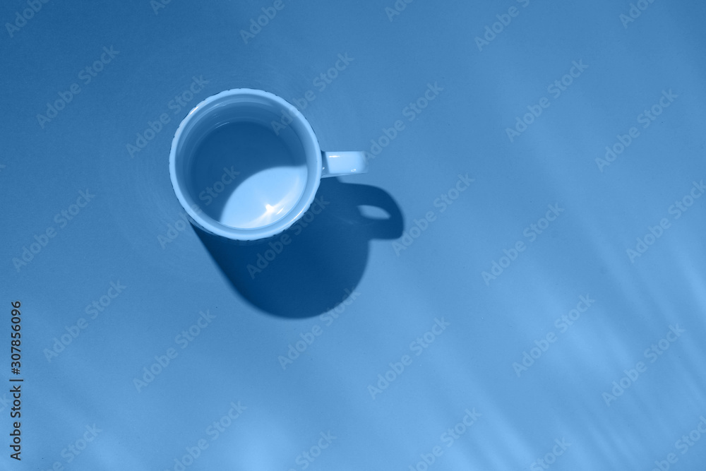 Empty tea cup on blue paper background. Coffee mug from above. Trendy color of the year 2020. Flat lay, top view.