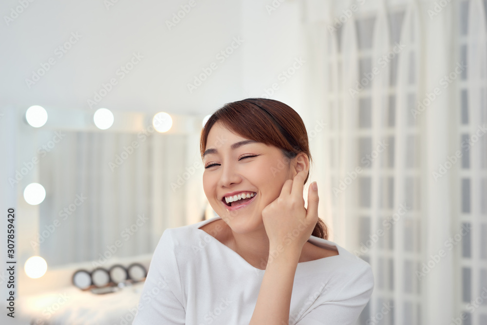 Cheerful young Asian woman touching her face with fresh skin Cheerful young Asian woman touching her face with fresh skin