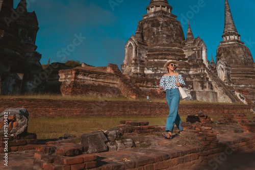 Tourist girl a portrait of fashion by pattern dot dress and jeans with sunglasses in Historic site at Ayutthaya Thailand