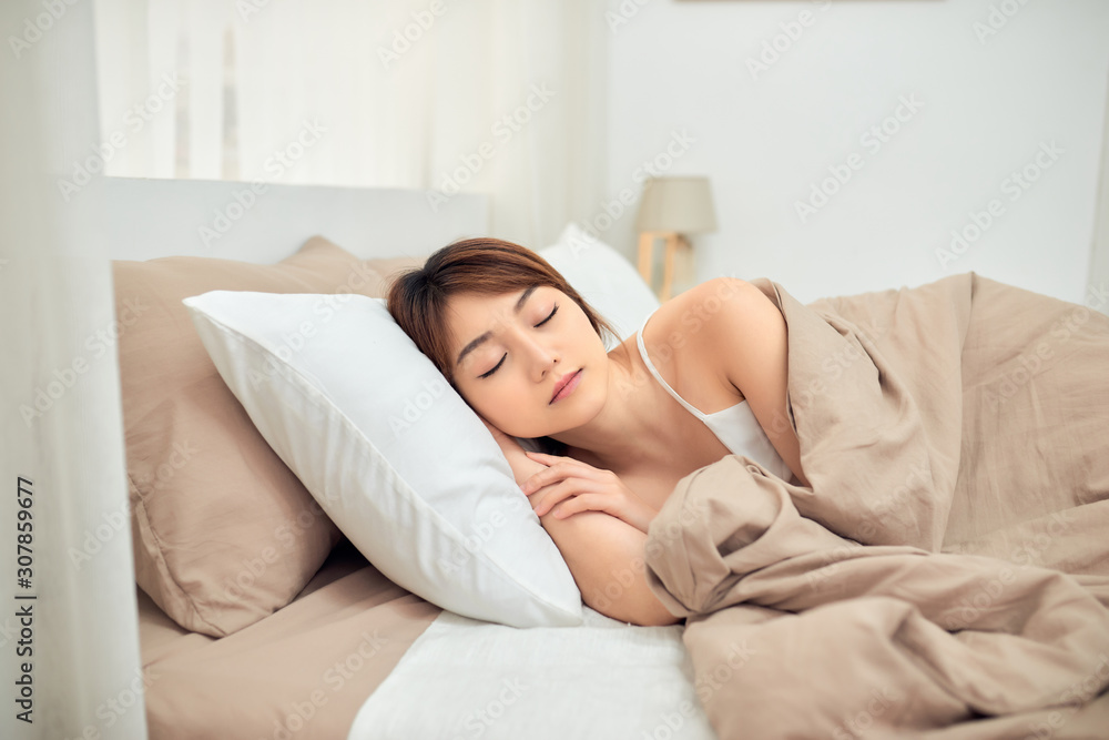 Beautiful young Asian woman sleeping while lying in her bed. Beautiful young Asian woman sleeping while lying in her bed.