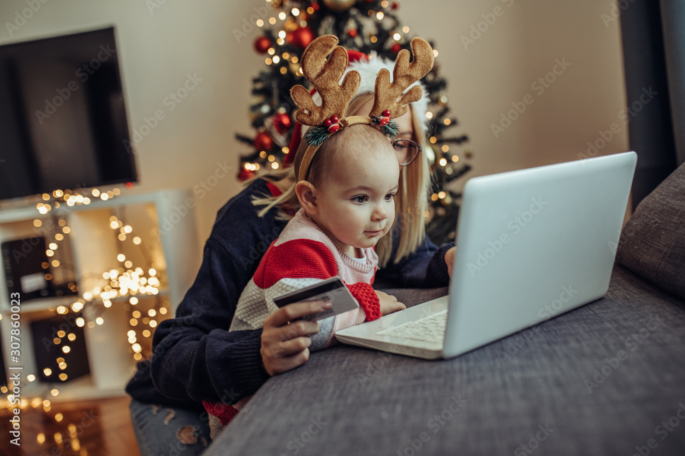 Woman and baby online shopping. Close up of a young woman and her baby buying presents online. Woman and baby online shopping. Close up of a young woman and her baby buying presents online.