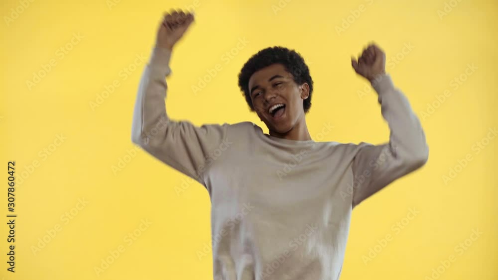 smiling african american teenager dancing isolated on yellow smiling african american teenager dancing isolated on yellow