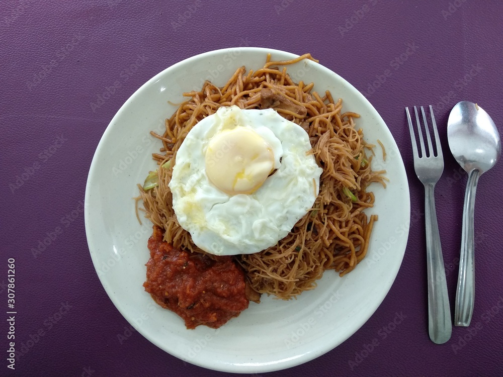 Tasty Fried noodle with sunny side up egg. Served on white plate. Top view close up detail