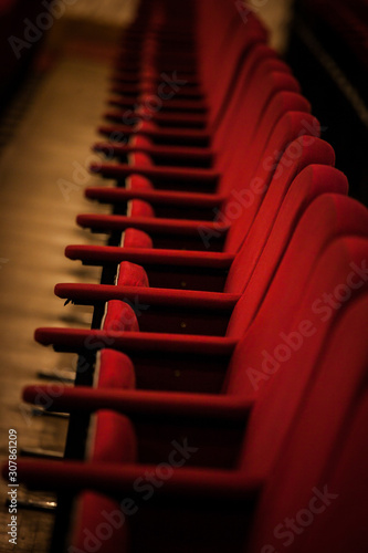  empty red seats in the auditorium in the half-darkness at a live performance. wine chairs