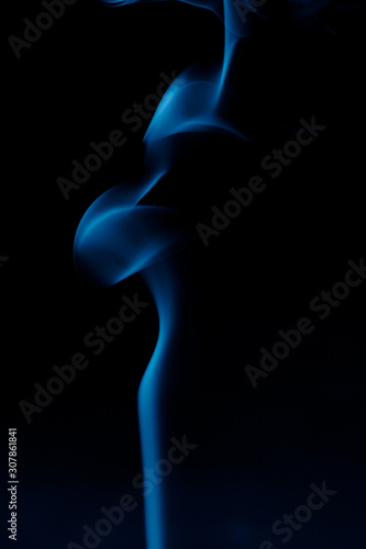 Silhouette of a woman from the smoke of incense sticks trendy classic blue on a dark background.