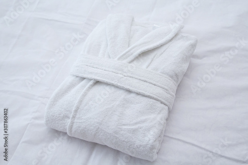 Clean folded bathrobe on white bed. photo