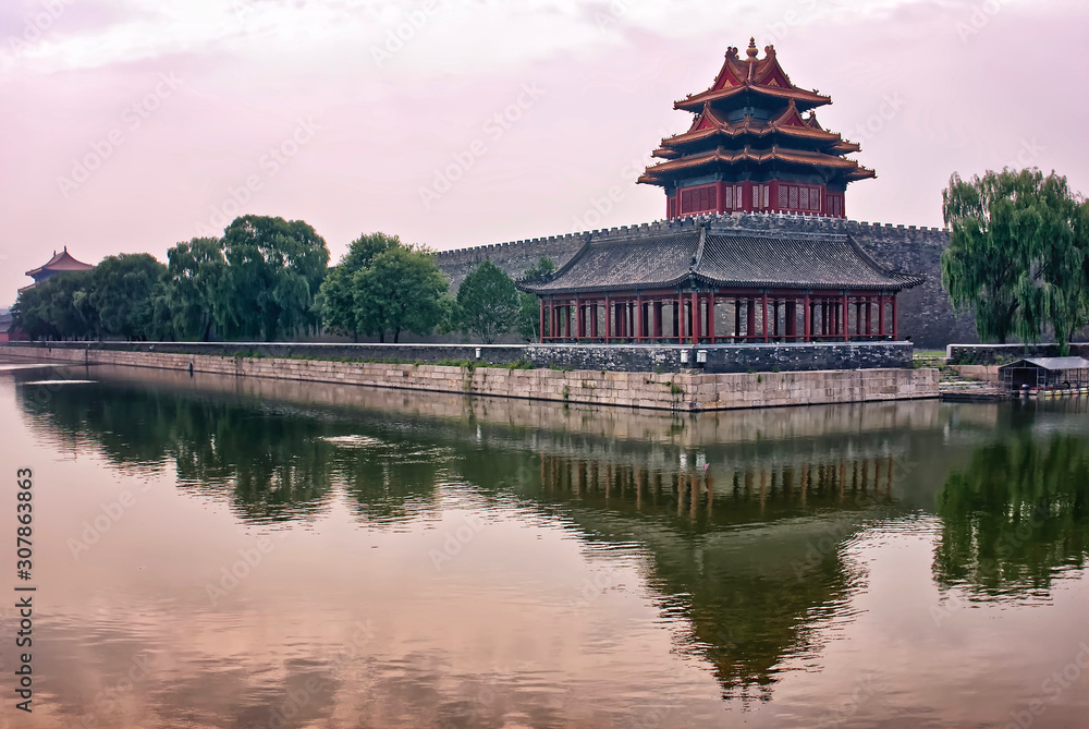 Corner Tower of Forbidden City under the outer Moat at dusk. tower and trees are reflected in the water Corner Tower of Forbidden City under the outer Moat at dusk. tower and trees are reflected in the water