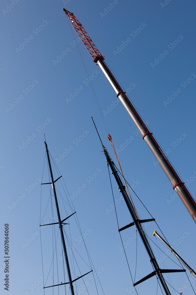 Placing a mast on a super sailing yacht. Shipyard. Shipbuilding industry. Placing a mast on a super sailing yacht. Shipyard. Shipbuilding industry.