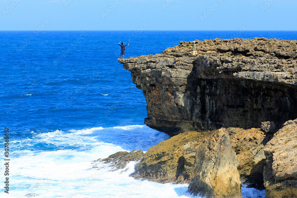 Yogyakarta, Indonesia, June 12, 2015. A tourist endangers his life by taking a selfie at the edge of a cliff at Timang Beach.