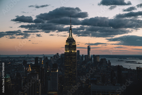 Aerial view of skyscrapers and towers in midtown skyline of Manhattan with evening sunset sky. Scenery cityscape of financial district with famous New York Landmark, illuminated Empire State Building