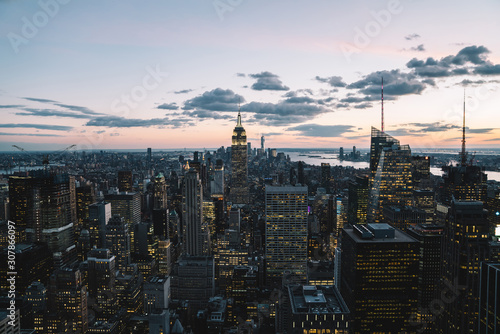 Aerial view of skyscrapers and towers in midtown skyline of Manhattan with evening sunset sky. Scenery cityscape of financial district with famous New York Landmark  illuminated Empire State Building