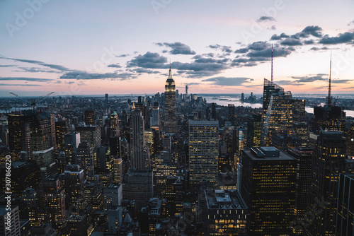 Aerial view of skyscrapers and towers in midtown skyline of Manhattan with evening sunset sky. Scenery cityscape of financial district with famous New York Landmark, illuminated Empire State Building