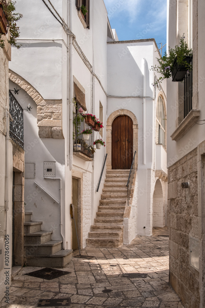 Narrow deserted street, stairs and white houses. Locorotondo, Italy.
