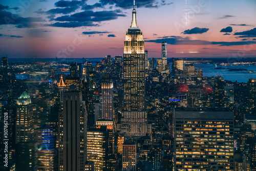 Aerial view of skyscrapers and towers in midtown skyline of Manhattan with evening sunset sky. Scenery cityscape of financial district with famous New York Landmark, illuminated Empire State Building