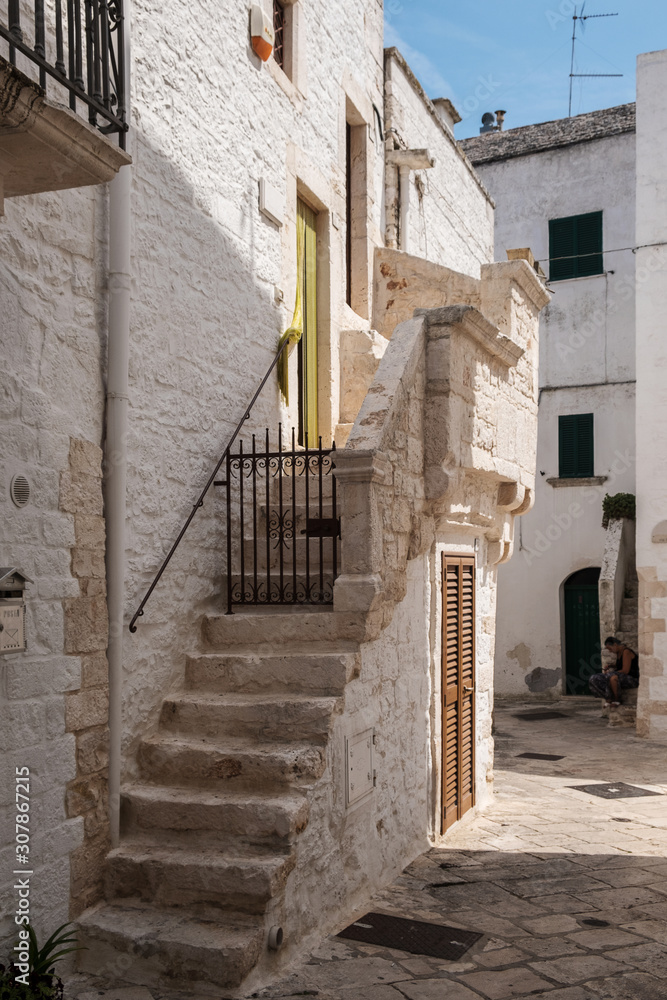 Obraz premium Narrow deserted street, stairs and white houses. Locorotondo, Italy.
