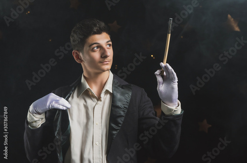  97 / 10000 АНГЛИЙСКИЙ Перевести вGoogleBing Magician with a magic wand on a dark background, charismatic young man in the image of an illusionist