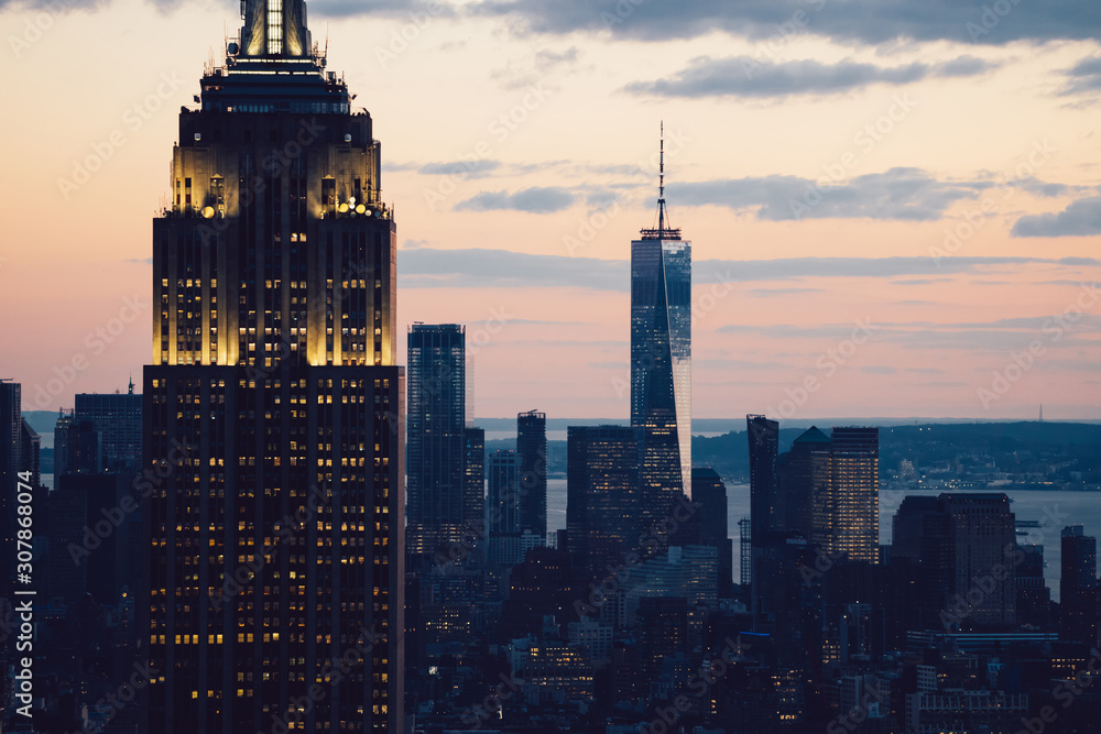 Cropped view of glowing skyscraper with beautiful sunset sky on background. Famous landmark Empire State Building with lighted facade, Scenery wallpaper