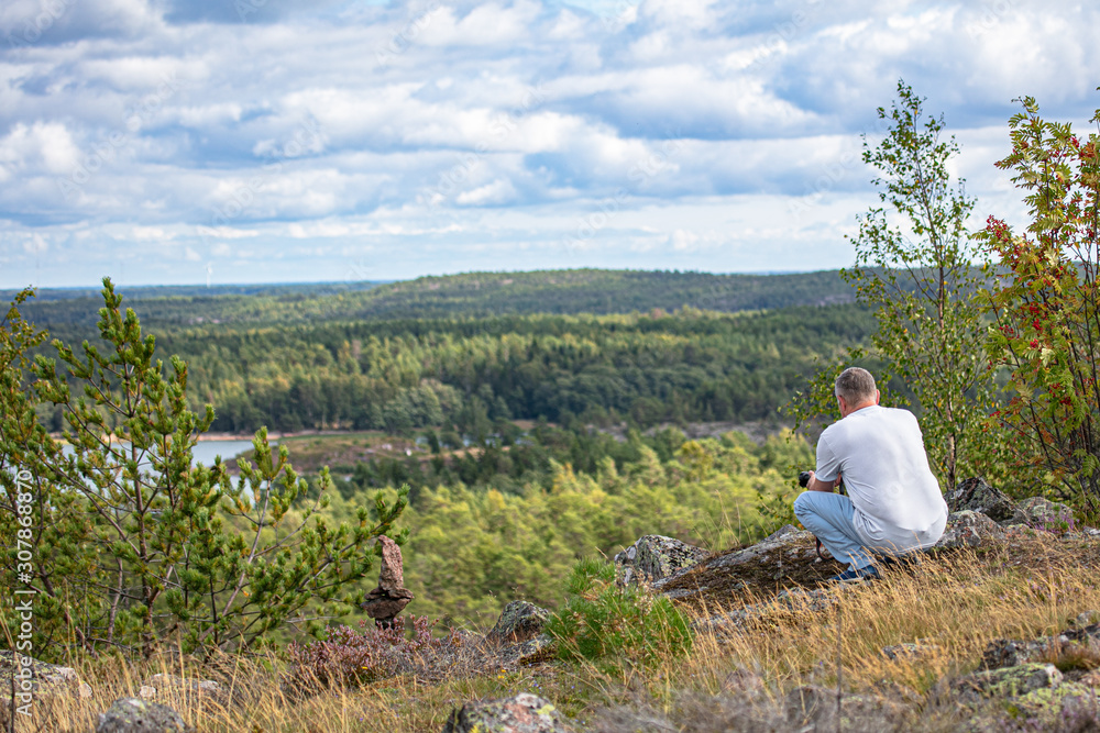 A man stands on a mountain, looks through binoculars, a beautiful sunny day A man stands on a mountain, looks through binoculars, a beautiful sunny day