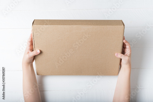 Rectangular cardboard box in children's hands. Top view, white background © somemeans