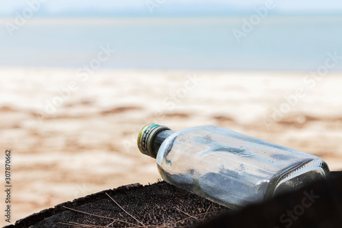 Empty used dirty glass bottles on the seaside. Ecological problem and environmental pollution. Glass bottles are non-degradable and abandoned on the coast.
