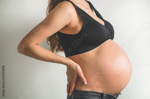 Attractive pregnant woman holding her belly. Last months of pregnancy