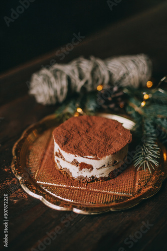 Christmas dessert - tiramisu on wooden background with Christmas tree and bokeh