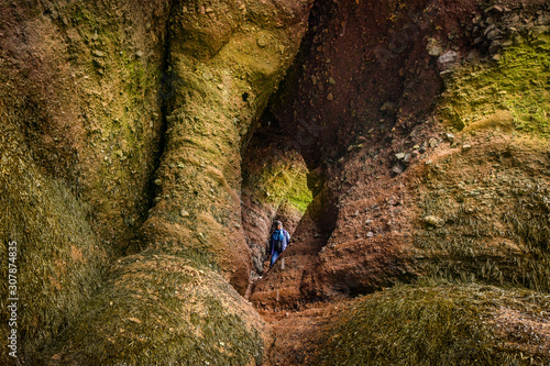 A tourist explores interesting passages carved by the Tidal waters of Bay of Fundy at Hopewell Rocks in New Brunswick, Canada