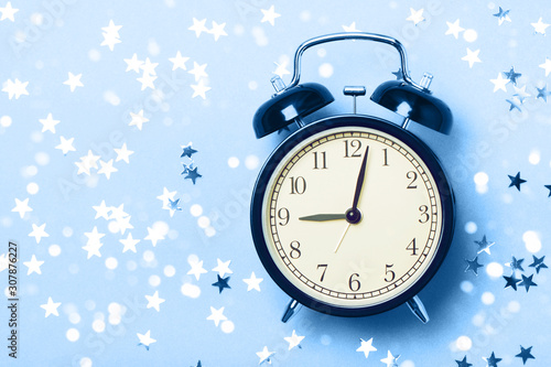 Alarm clock on a blue background with stars. The concept of preparing for sleep, an evening fairy tale, sweet dreams, etc.