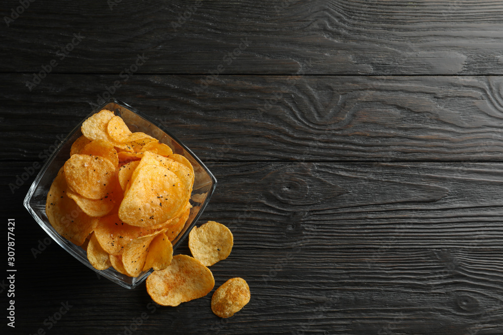 Potato chips in a place on wooden background, space for text. Top view
