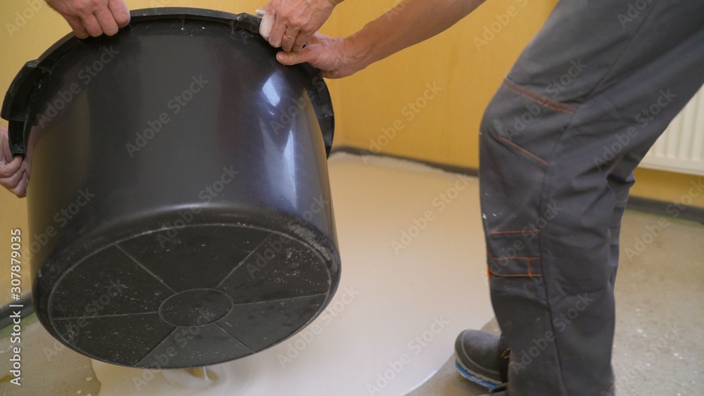 Liquid flooring. Leveling the floor with a liquid composition. Industrial worker at a cement