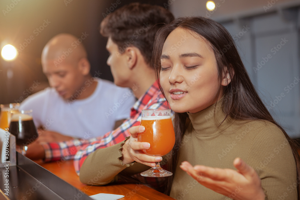 Young Asian woman enjoying drinking delicious beer at the pub with her friends Young Asian woman enjoying drinking delicious beer at the pub with her friends