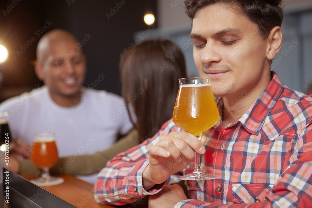 Cropped shot of a handsome young man enjoying aroma of delicious beer in his glass. Happy man having beer at the pub Cropped shot of a handsome young man enjoying aroma of delicious beer in his glass. Happy man having beer at the pub