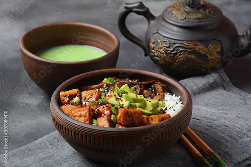 Sweet, spicy , crispy and fried Tofu in a bowl with terriayaki sauce, avocado,fried mushrooms, sesame seeds and rice. Served with green Matcha Tea. Healthy vegan food, gluten-free