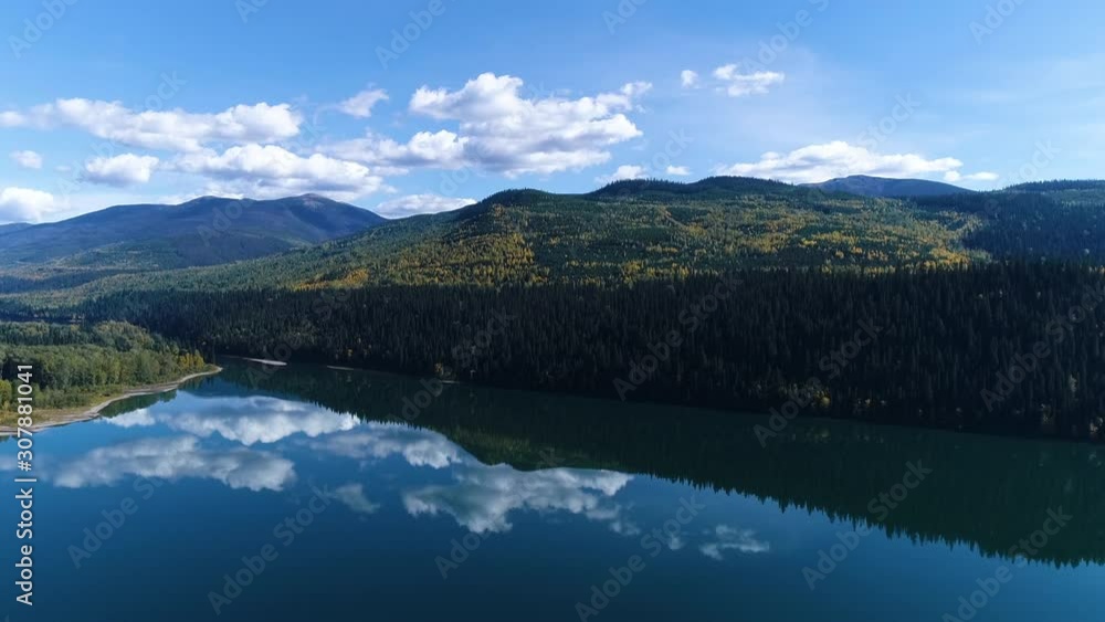 Steady, aerial, wide shot of a mountainous forests and a beautifully still lake with the reflections of the sky and clouds. Steady, aerial, wide shot of a mountainous forests and a beautifully still lake with the reflections of the sky and clouds.