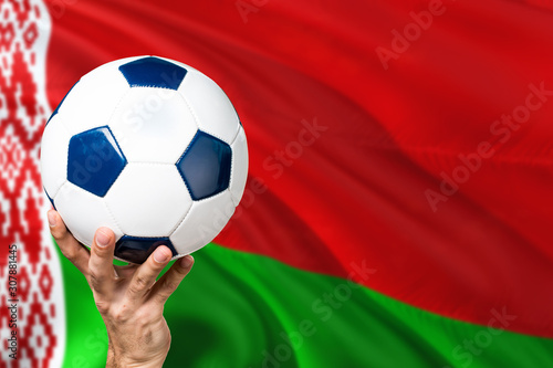 Belarus soccer concept. National team player hand holding soccer ball with country flag background. Copy space for text.