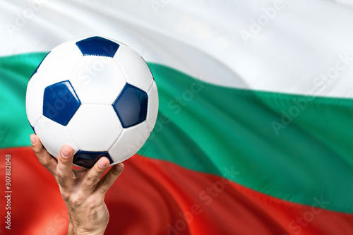Bulgaria soccer concept. National team player hand holding soccer ball with country flag background. Copy space for text.