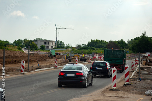 Cars riding on the road works area. Workers are building new road on a summer day. © diesirae