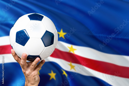 Cape Verde soccer concept. National team player hand holding soccer ball with country flag background. Copy space for text.