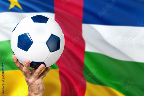 African Republic soccer concept. National team player hand holding soccer ball with country flag background. Copy space for text.