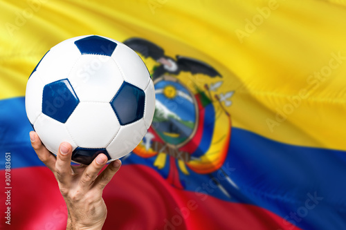 Ecuador soccer concept. National team player hand holding soccer ball with country flag background. Copy space for text.