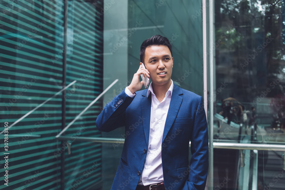 Asian businessman talking on phone in office building Asian businessman talking on phone in office building