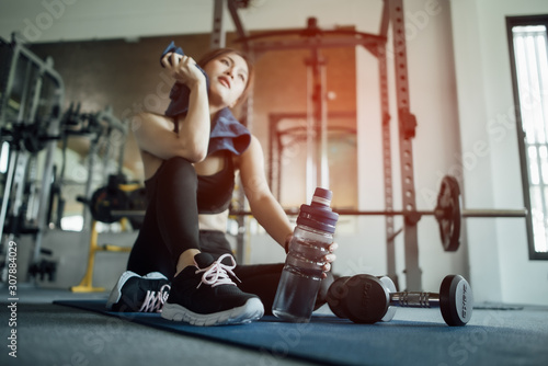 Young woman drinking water and taking a break after workout in gym,fitness concept.