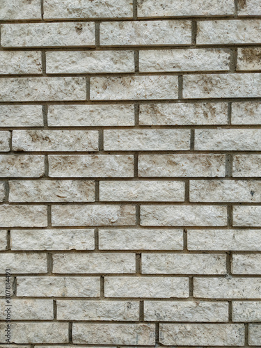 Rock stone wall background made of bricks on a wall of the building in the outdoors facade with rough texture and interesting natural material pattern