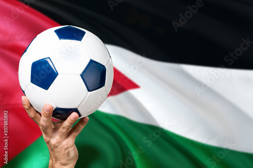 Jordan soccer concept. National team player hand holding soccer ball with country flag background. Copy space for text.