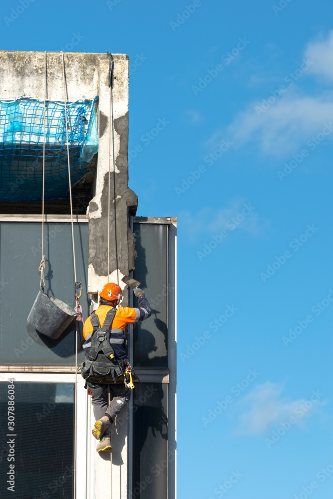 trabajador vertical reparando una fachada ó trabajador vertical colgado de una cuerda reparando una fachada con cemento trabajador vertical reparando una fachada ó trabajador vertical colgado de una cuerda reparando una fachada con cemento