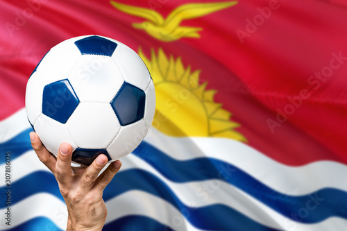 Kiribati soccer concept. National team player hand holding soccer ball with country flag background. Copy space for text.