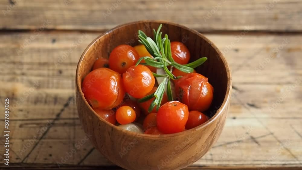 A woman's hand adorns a bowl of canned tomatoes with a fresh green sprig of rosemary. Close up. A woman's hand adorns a bowl of canned tomatoes with a fresh green sprig of rosemary. Close up.
