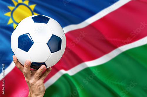 Namibia soccer concept. National team player hand holding soccer ball with country flag background. Copy space for text.