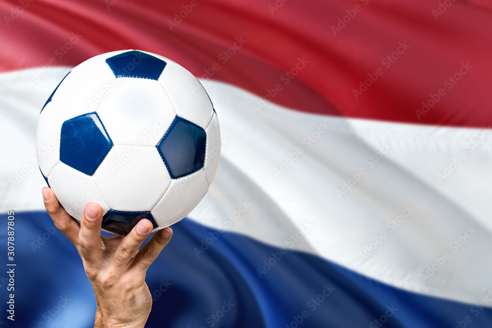 Naklejka premium Netherlands soccer concept. National team player hand holding soccer ball with country flag background. Copy space for text.